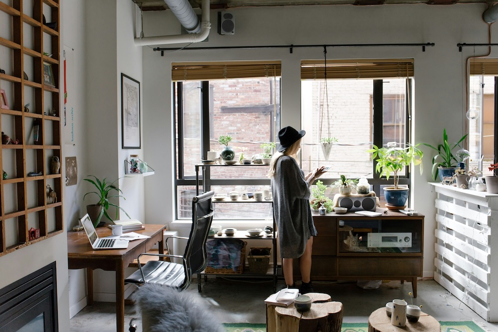 Someone at home in their apartment, tending the plants on the windowsill